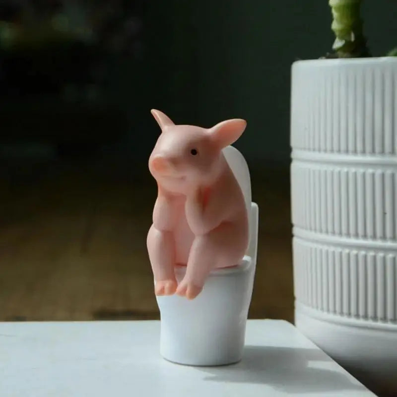 Figurine de cochon assise sur les toilettes